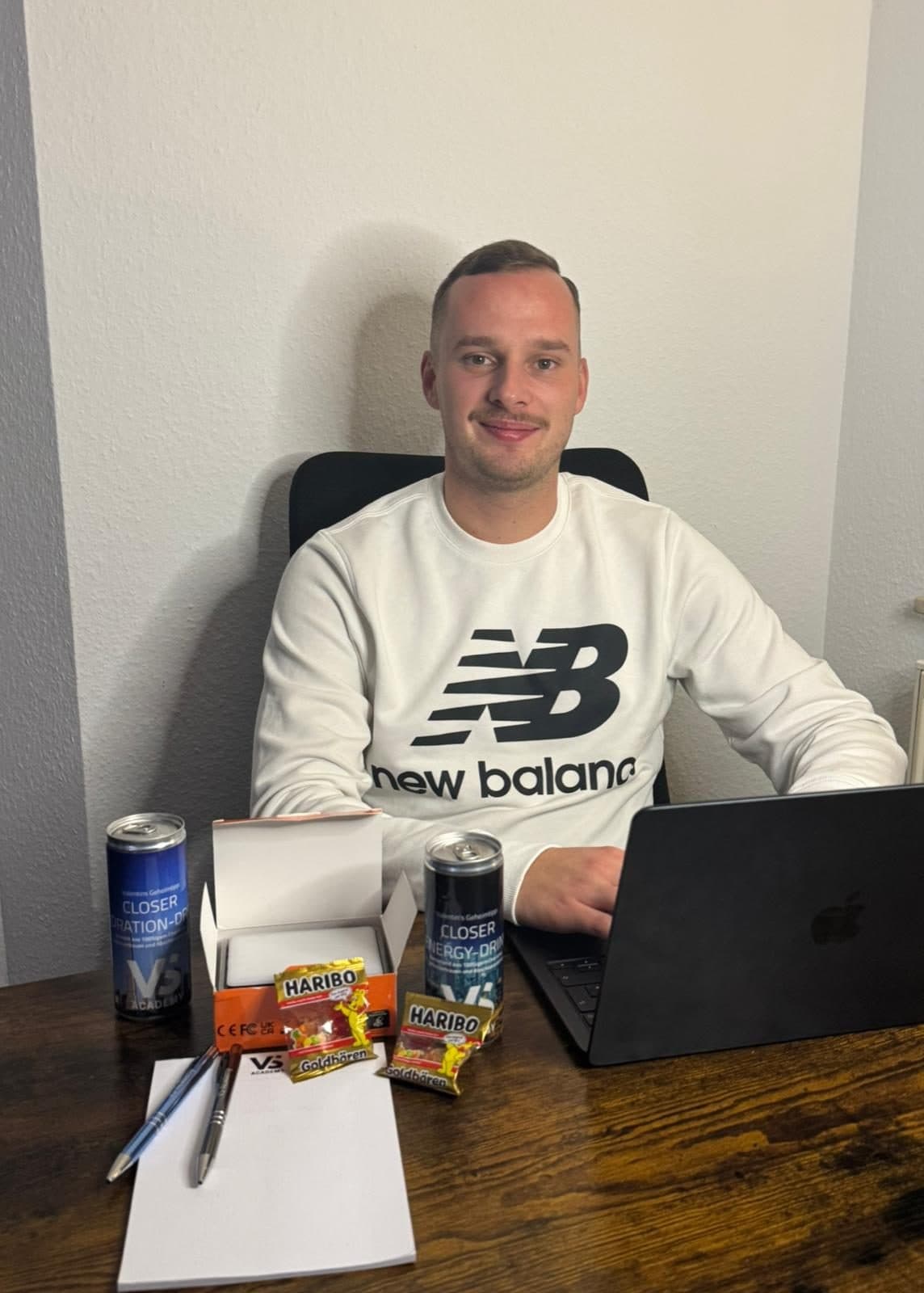 Teilnehmer am Schreibtisch mit Laptop, davor Dosen, Block und Haribo